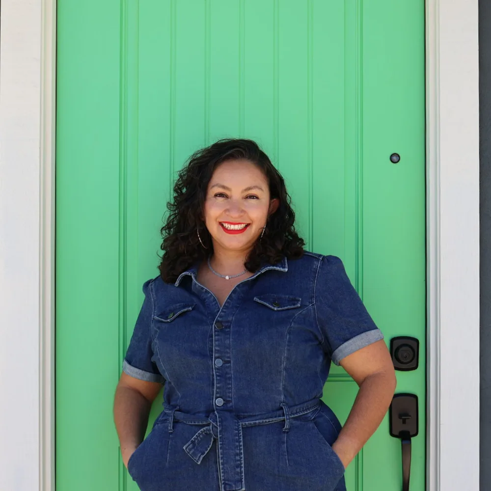 Karyna Valdez smiling in front of a green front door